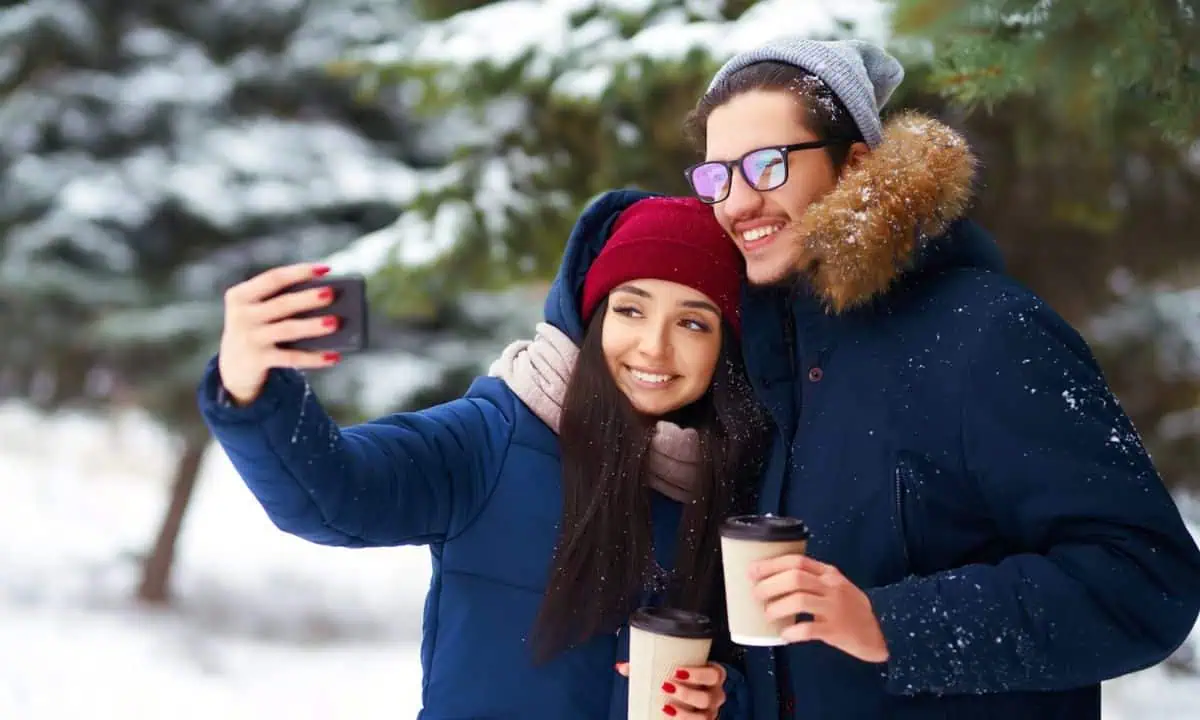 Couple man and woman in winter snow taking selfie