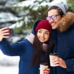 Couple man and woman in winter snow taking selfie