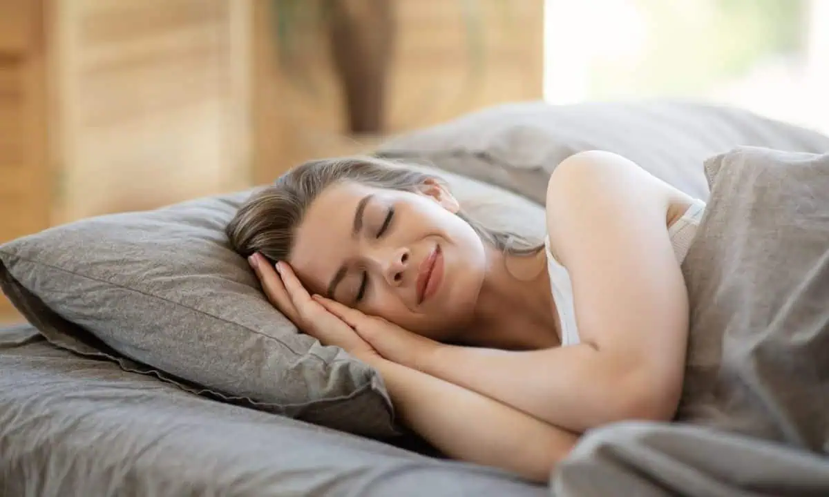 Young woman sleeping in hotel bed covered with blanket