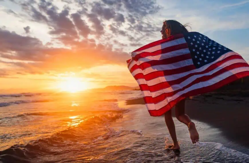 Young girl running down the beach with an American flag