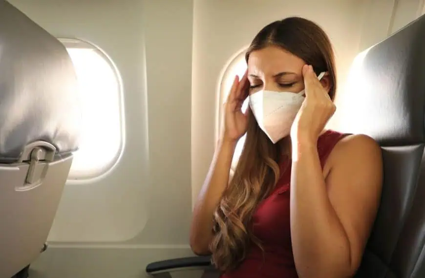 woman with headache on airplane with mask